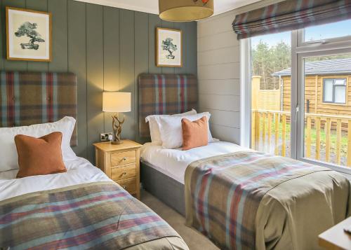a bedroom with two beds and a window with a view at Thirlestane Woodland Lodges in Lauder