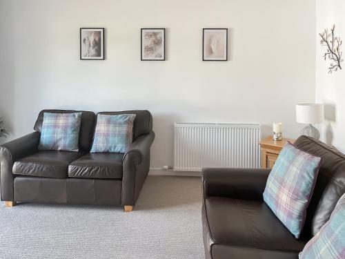 a living room with a leather couch and a chair at No 8 Cottage in Aviemore