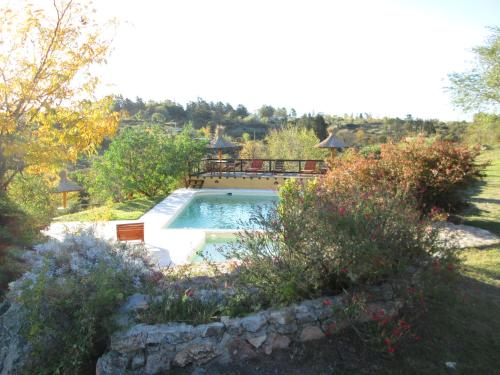 a swimming pool in a garden with a gazebo at Cabañas Ojos del Viento in Villa Giardino