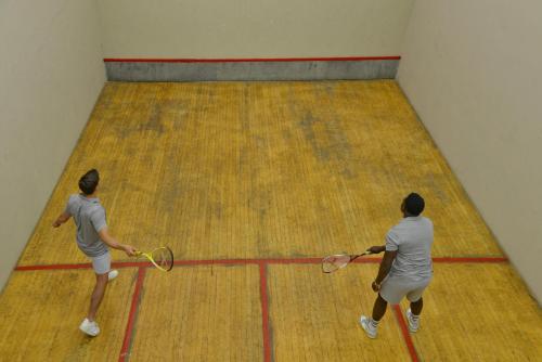 three men playing a game of tennis on a court at Elephant Hills Resort in Victoria Falls