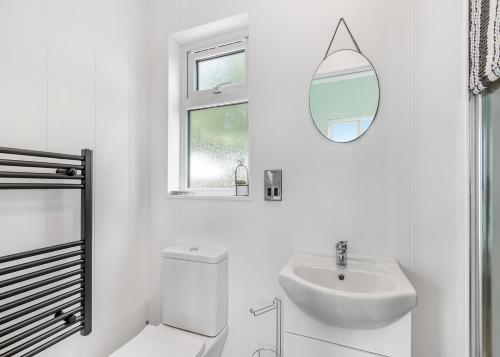 a white bathroom with a sink and a mirror at Calvesland Hideaway in Manorbier