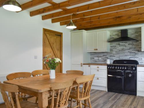 a kitchen with a wooden table with chairs and a stove at Kirkstall Wood Farm in Ingrow
