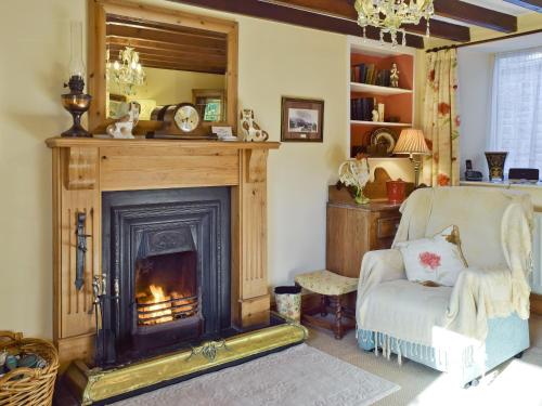 ein Wohnzimmer mit Kamin und Sessel in der Unterkunft Harriet's Cottage in Muker