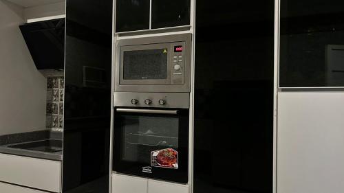 Un horno microondas en una cocina junto a una estufa. en شقة الزهور, en Al Nairyah