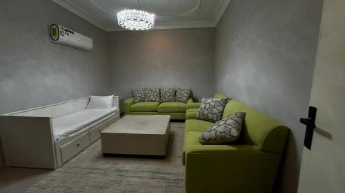 una sala de estar con un sofá y una cama en شقة الزهور, en Al Nairyah