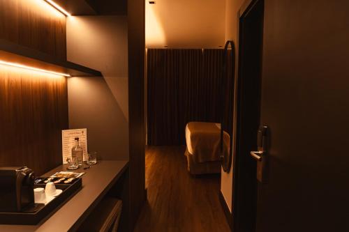 a bathroom with a sink and a room with a chair at Pousada Murano in Campos do Jordão