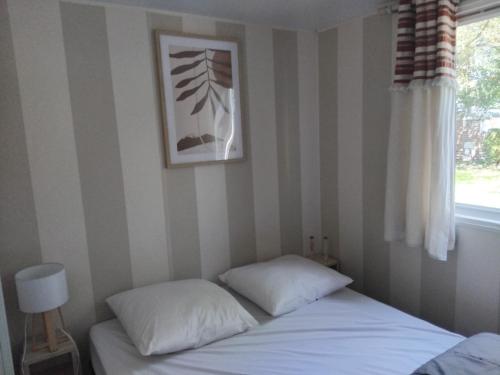 a bed with two pillows in a room with a window at Mobil-home à 11km d'Europa Park via le bac in Boofzheim