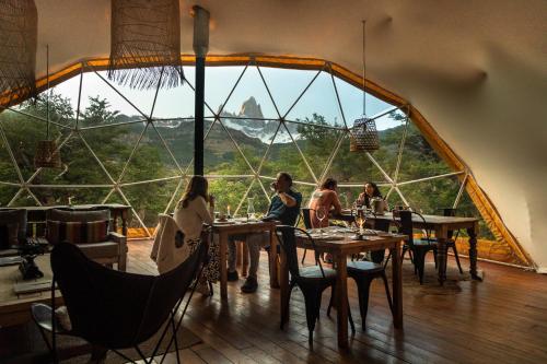 a group of people sitting at tables in a room with a large window at Chalten Camp - Glamping with a view in El Chalten