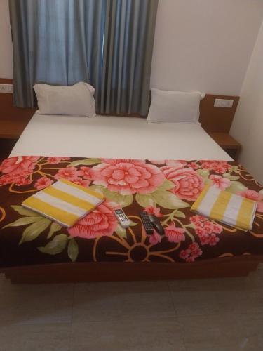 a bed with a floral bedspread and two pillows on it at Naksh Villa in Mahabaleshwar