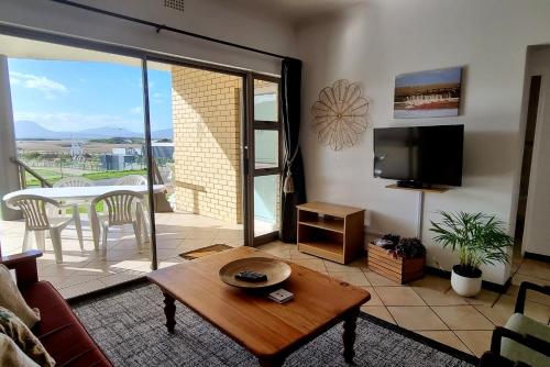 a living room with a table and a tv at Kleinmond Panorama Holidays in Kleinmond