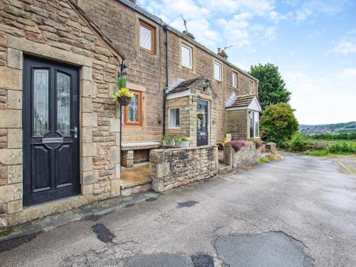 a stone house with a black door on a street at Weavers Cottage in Barrowford