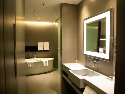 a bathroom with a tub and a sink and a mirror at Novotel Kolkata Hotel and Residences in Kolkata