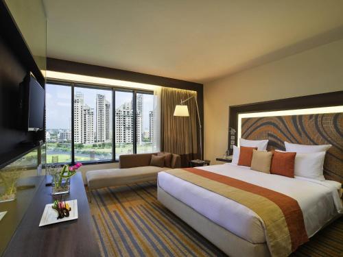 a hotel room with a large bed and a large window at Novotel Kolkata Hotel and Residences in Kolkata