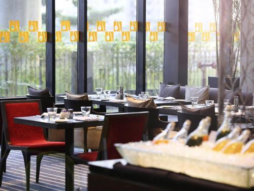 a dining room with tables and chairs and windows at Novotel Kolkata Hotel and Residences in Kolkata
