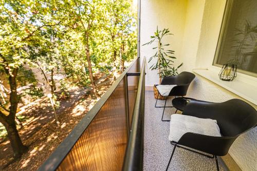a balcony with chairs and a view of trees at Móriczka Apartman in Hódmezővásárhely
