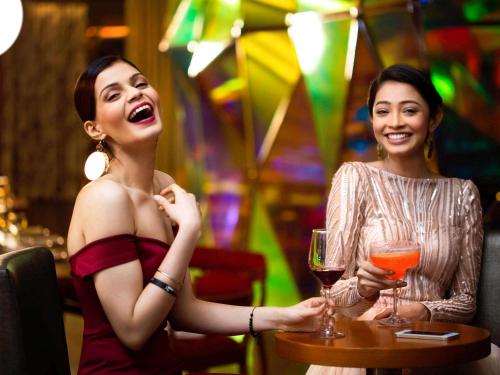 two women sitting at a table with glasses of wine at Novotel Kolkata Hotel and Residences in Kolkata