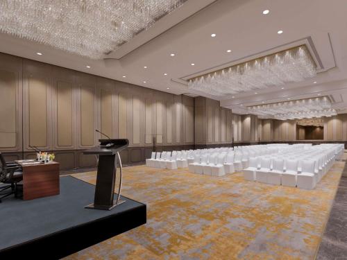 a conference room with white chairs and a podium at Novotel Kolkata Hotel and Residences in Kolkata