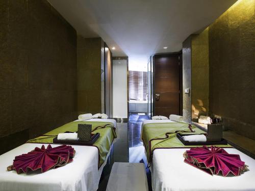a room with three beds with white and green sheets at Novotel Kolkata Hotel and Residences in Kolkata