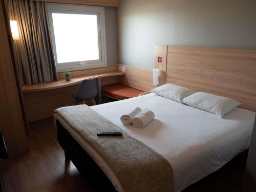 a bedroom with a bed with two towels on it at ibis Concepcion in Concepción