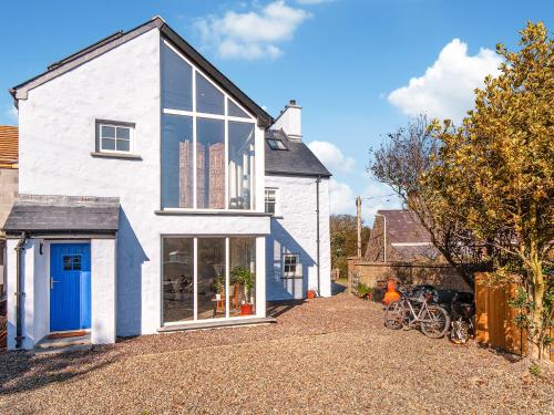 una casa bianca con una porta blu e alcune biciclette di The Loft - Cottage a Letterston