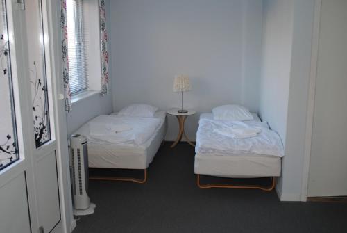 a room with two beds and a table with a lamp at Det Lille Hotel in Rønne