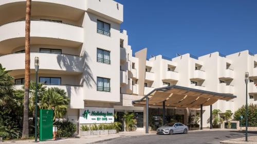 a car parked in front of a building at Holiday Inn Algarve Albufeira by IHG in Albufeira