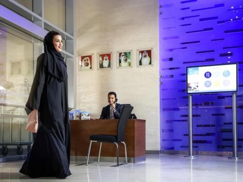 a woman in a hijab standing in front of a desk at Novotel Abu Dhabi Gate in Abu Dhabi