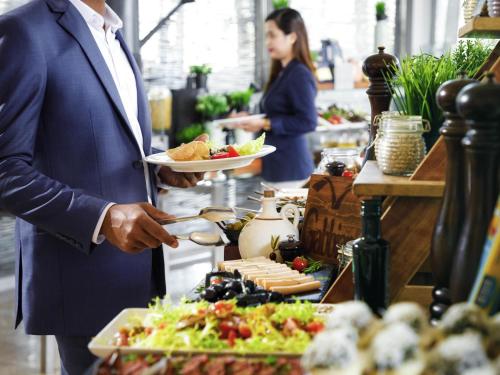 a man holding a plate of food in a buffet at Novotel Abu Dhabi Gate in Abu Dhabi