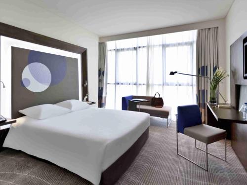 a hotel room with a large white bed and a desk at Novotel Abu Dhabi Gate in Abu Dhabi