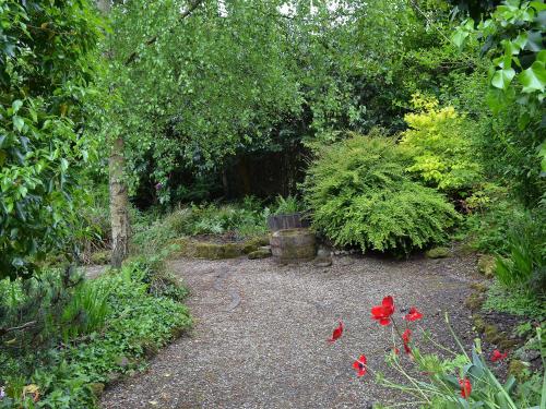 a garden with some red flowers and trees at Arne Barn in Arne