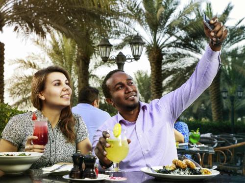 a man and a woman sitting at a table eating food at Novotel Abu Dhabi Gate in Abu Dhabi