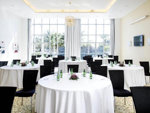 a banquet room with white tables and black chairs at Novotel Abu Dhabi Gate in Abu Dhabi
