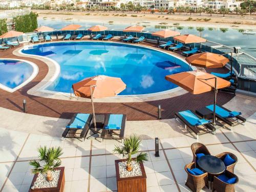 an overhead view of a pool with chairs and umbrellas at Novotel Abu Dhabi Gate in Abu Dhabi