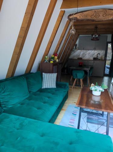 uma sala de estar com um sofá verde e uma mesa em A Frame Scorilo em Poiana Mărului