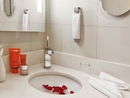 a bathroom with a sink with red paper on it at Ibis Abu Dhabi Gate in Abu Dhabi