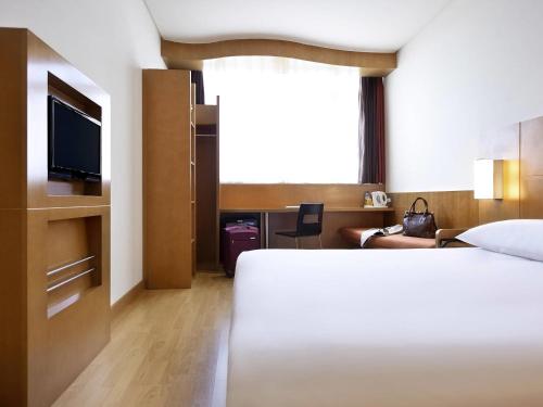 a hotel room with a bed and a television at Ibis Abu Dhabi Gate in Abu Dhabi