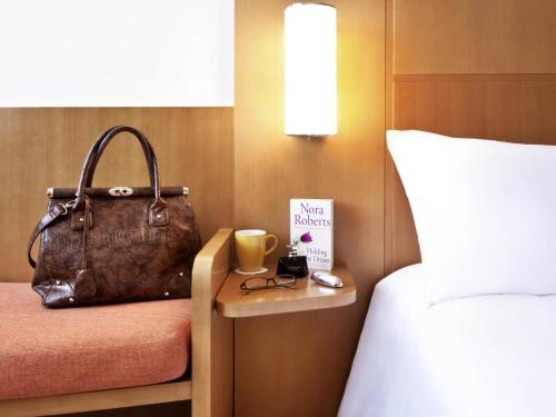 a hotel room with a bed and a purse on a table at Ibis Abu Dhabi Gate in Abu Dhabi