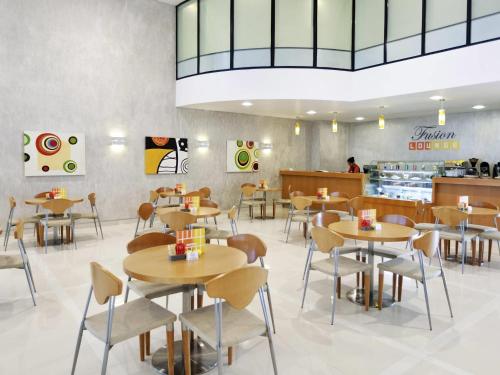 a restaurant with tables and chairs and a counter at Ibis Abu Dhabi Gate in Abu Dhabi