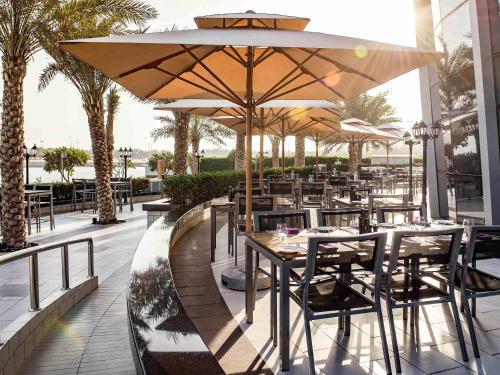 a restaurant with tables and chairs with umbrellas at Ibis Abu Dhabi Gate in Abu Dhabi