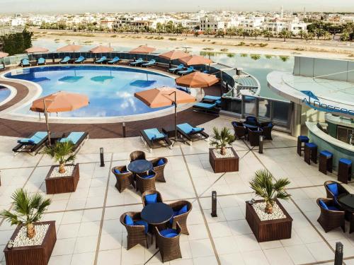 an overhead view of a resort pool with tables and chairs at Ibis Abu Dhabi Gate in Abu Dhabi