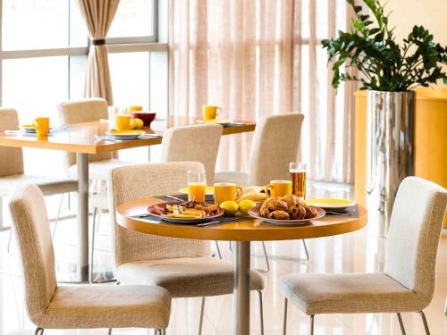 a table and chairs with a plate of food on it at Ibis Abu Dhabi Gate in Abu Dhabi