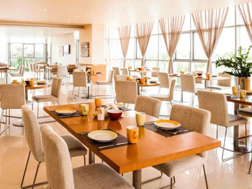 a dining room with tables and chairs and windows at Ibis Abu Dhabi Gate in Abu Dhabi