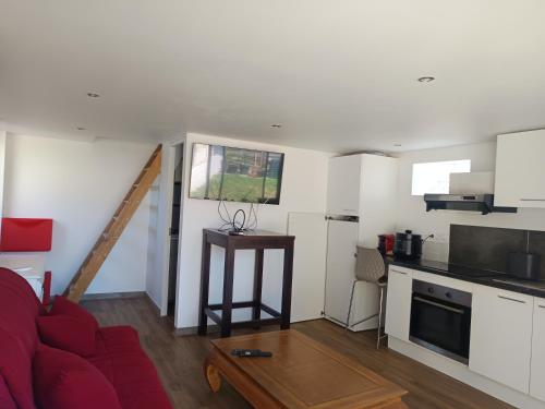 ein Wohnzimmer mit einem roten Sofa und einer Küche in der Unterkunft Dépendance meublée avec terrasse in Carbon-Blanc