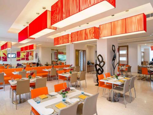 a dining room with tables and chairs and orange chairs at ibis Bengaluru Hosur Road - An Accor Brand in Bengaluru