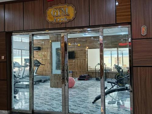 a gym with glass doors and a gym with exercise equipment at Immaculate Excellence Luxury Hotels Ltd in Owerri