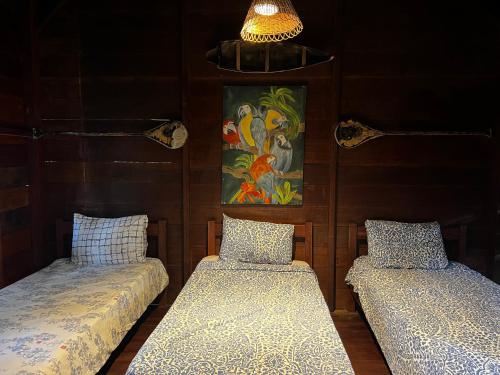 two beds in a room with a painting on the wall at CasAmor Hostel in Alter do Chao
