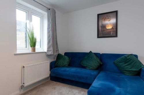 a blue couch in a living room with a window at Bright & Modern 4 Bedroom House in Yeovil in Over Compton