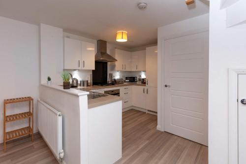 a kitchen with white cabinets and a counter top at Bright & Modern 4 Bedroom House in Yeovil in Over Compton