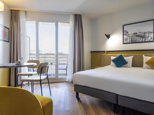 a hotel room with a large bed and a table at Aparthotel Adagio Paris Montrouge in Montrouge