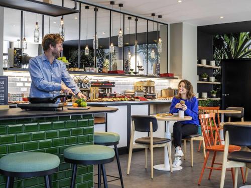 a man and a woman sitting at a table in a kitchen at Aparthotel Adagio Paris Montrouge in Montrouge